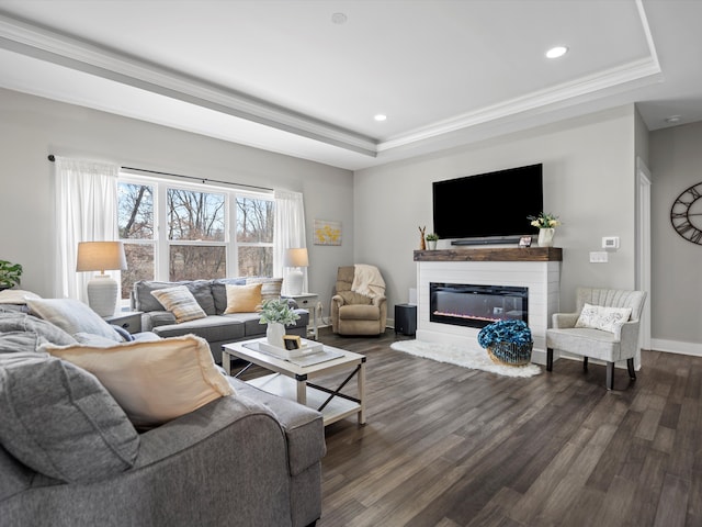 living area with baseboards, a tray ceiling, recessed lighting, dark wood-style floors, and a glass covered fireplace