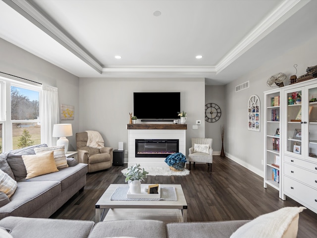 living area featuring a raised ceiling, dark wood-style floors, visible vents, and baseboards