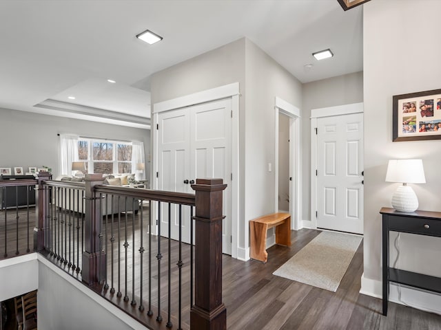 entryway featuring a raised ceiling, recessed lighting, dark wood-style flooring, and baseboards