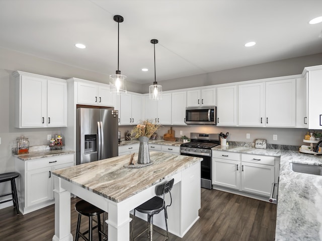 kitchen featuring a sink, a kitchen breakfast bar, dark wood finished floors, stainless steel appliances, and white cabinets