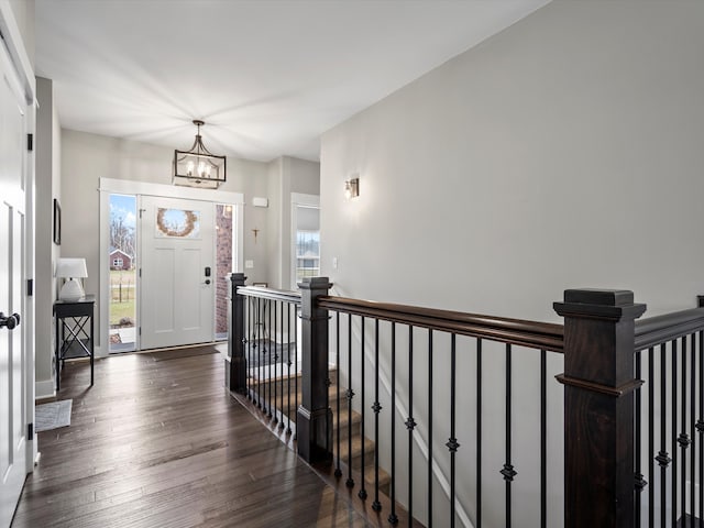 foyer entrance featuring baseboards, dark wood-type flooring, and a chandelier