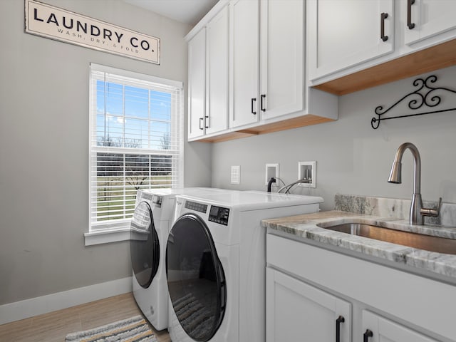 laundry room with baseboards, washer and dryer, wood finished floors, cabinet space, and a sink