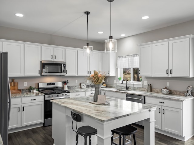 kitchen with a sink, white cabinetry, appliances with stainless steel finishes, a breakfast bar area, and dark wood-style flooring