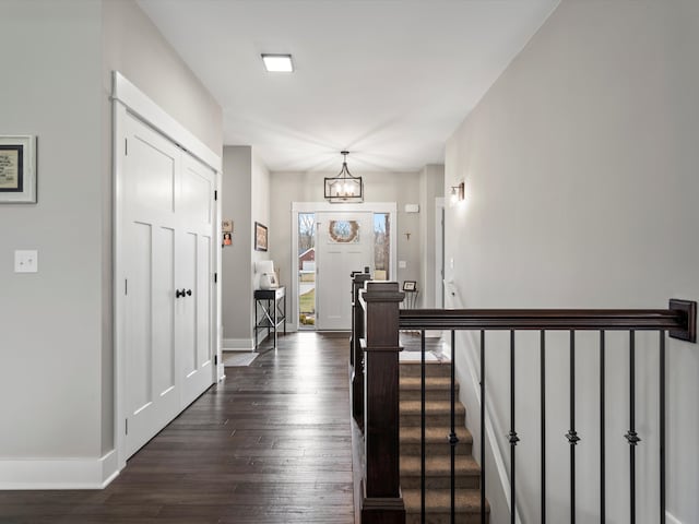 entrance foyer with stairs, dark wood-type flooring, baseboards, and a chandelier