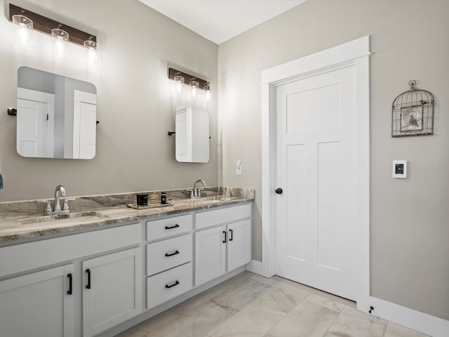 full bathroom with double vanity, marble finish floor, baseboards, and a sink