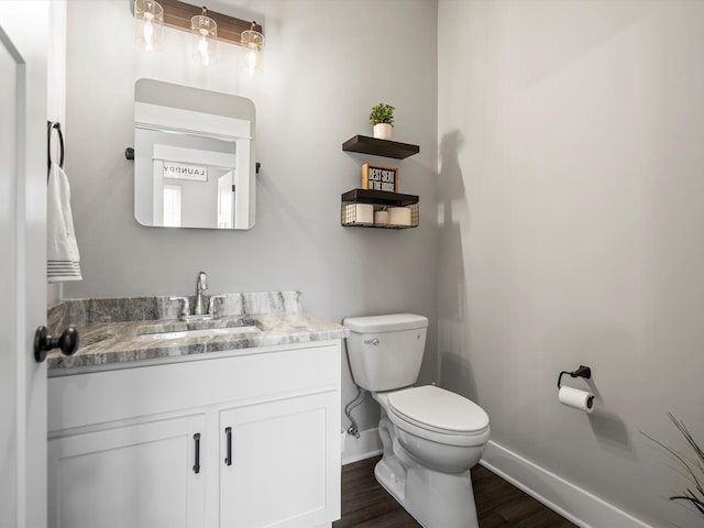 bathroom with baseboards, toilet, wood finished floors, and vanity