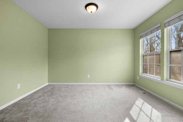 carpeted spare room with visible vents and baseboards