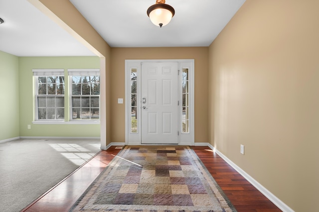 entryway featuring carpet floors, baseboards, and wood finished floors