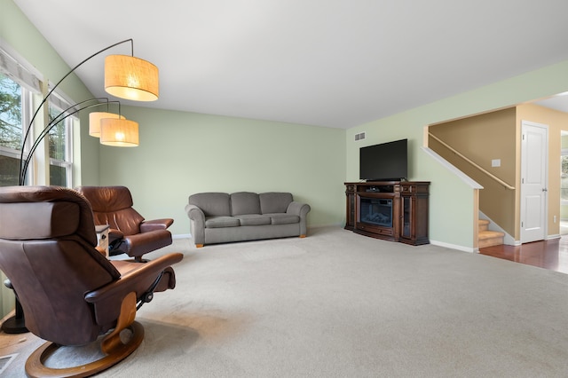 carpeted living area with stairs, baseboards, and a fireplace