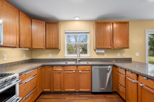 kitchen with a sink, brown cabinetry, dark wood-style flooring, and stainless steel appliances