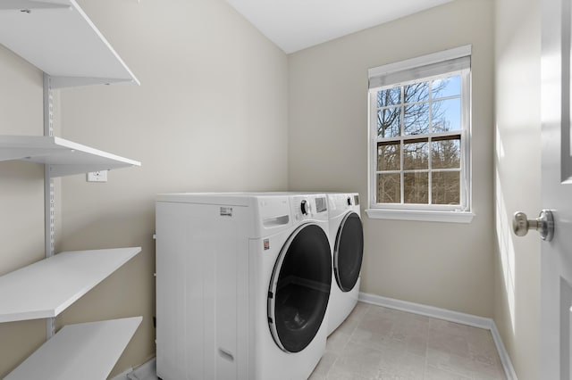 washroom with baseboards, washing machine and dryer, and laundry area