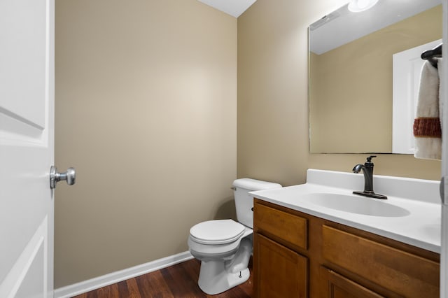 bathroom with baseboards, toilet, wood finished floors, and vanity