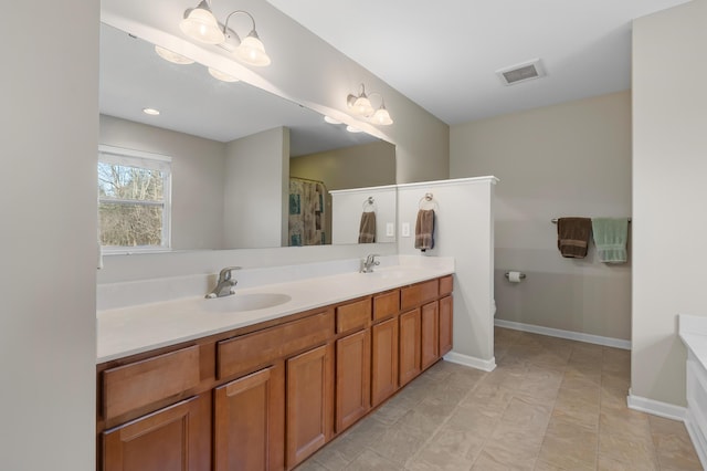 bathroom featuring a sink, visible vents, baseboards, and double vanity