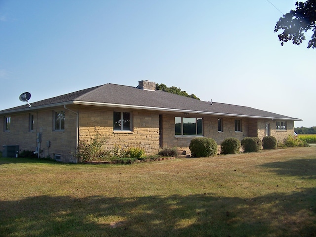 rear view of house featuring a lawn, stone siding, central AC, and a chimney