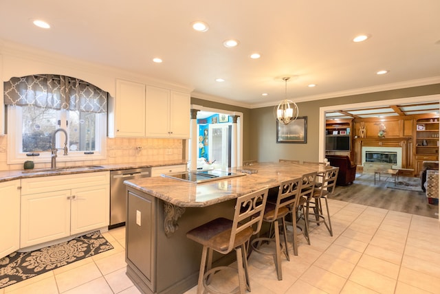 kitchen featuring a glass covered fireplace, a sink, stainless steel dishwasher, crown molding, and black electric cooktop