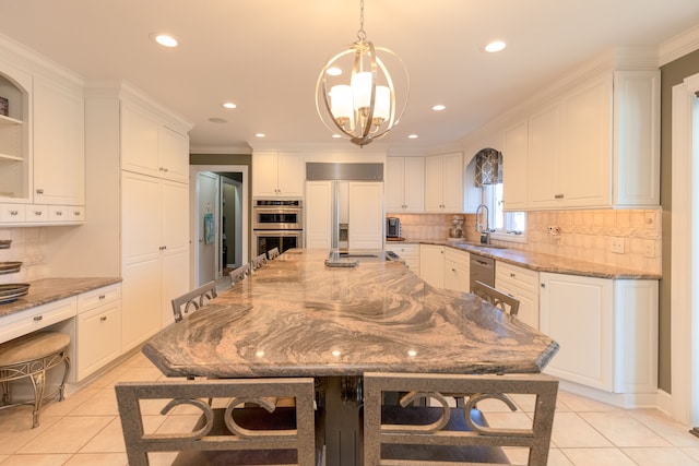 kitchen with light stone counters, white cabinetry, appliances with stainless steel finishes, a breakfast bar area, and light tile patterned flooring