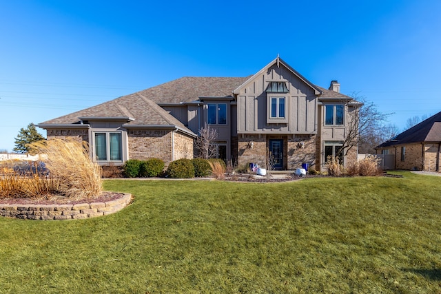 view of front facade featuring a front yard, brick siding, board and batten siding, and a shingled roof