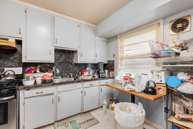 kitchen featuring decorative backsplash, gas range, dark countertops, and white cabinets