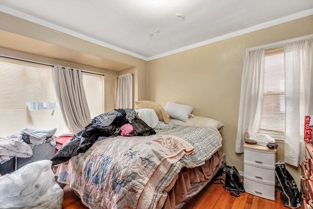 bedroom with multiple windows, ornamental molding, and wood finished floors