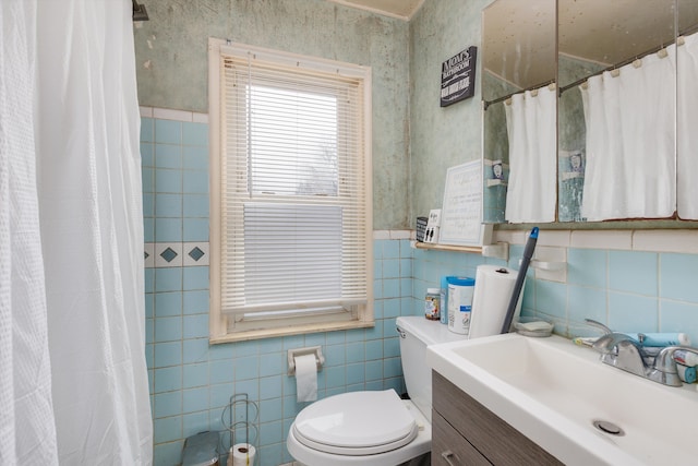 bathroom with tile walls, a shower with shower curtain, toilet, and vanity