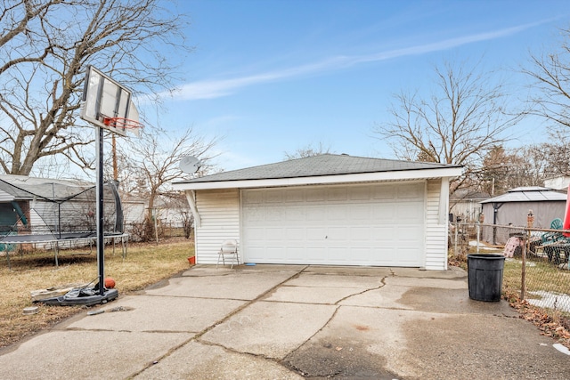 detached garage with a trampoline and fence