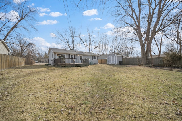 rear view of house featuring a shed, a yard, a fenced backyard, an outdoor structure, and a deck