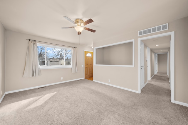 unfurnished room with visible vents, carpet flooring, baseboards, and ceiling fan