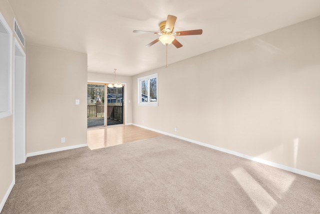 unfurnished room with ceiling fan with notable chandelier, carpet, visible vents, and baseboards