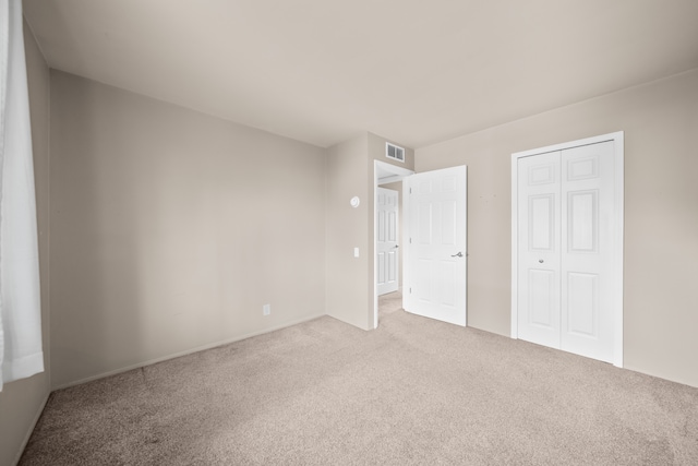 unfurnished bedroom with carpet, visible vents, and a closet