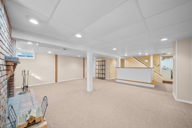 basement featuring a drop ceiling, carpet flooring, and baseboards