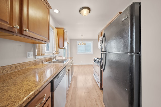 kitchen featuring an inviting chandelier, a sink, stainless steel appliances, light wood-style floors, and brown cabinets