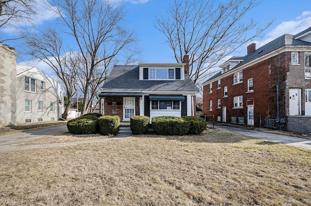 view of front facade with brick siding and a chimney