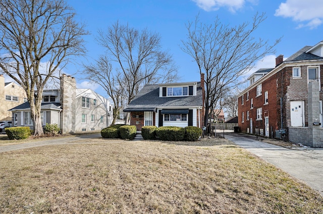 view of front of home with a residential view, brick siding, and a front lawn