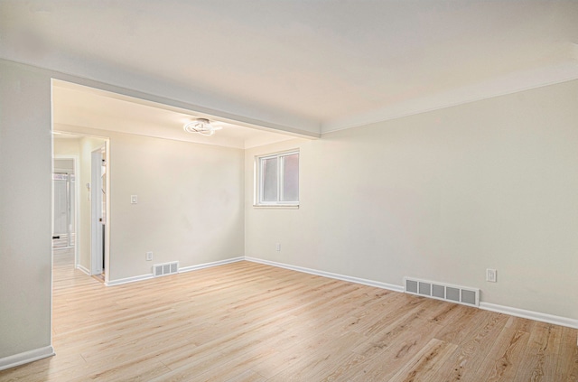 empty room featuring visible vents, baseboards, and light wood-style floors