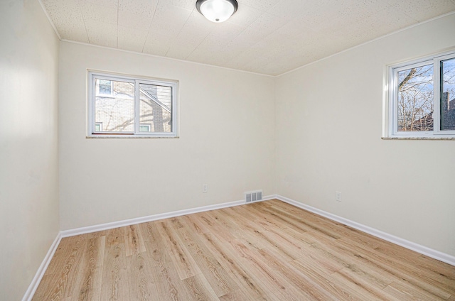 spare room featuring visible vents, baseboards, and wood finished floors