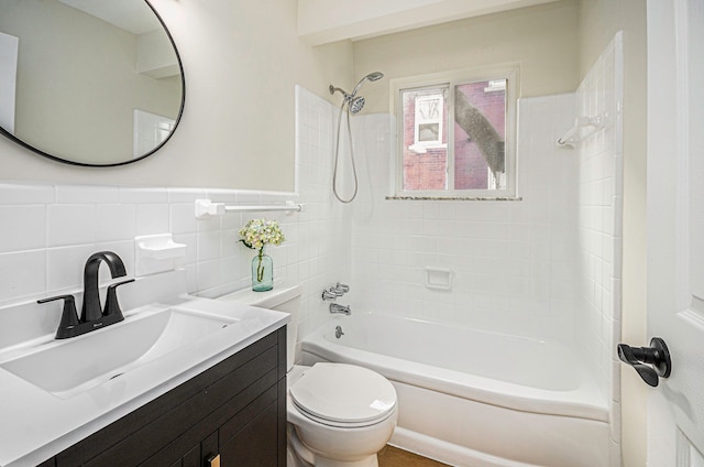 bathroom featuring vanity, wainscoting, bathing tub / shower combination, toilet, and tile walls