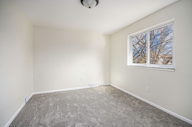 empty room featuring carpet, visible vents, and baseboards