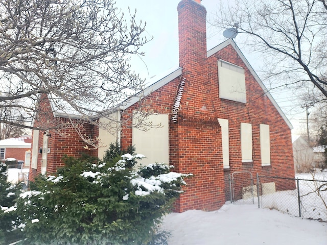 20048 Fleming St, Detroit, MI 48234 - view of snowy exterior featuring brick siding, fence, and a chimney