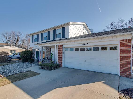 traditional-style house featuring brick siding, concrete driveway, and an attached garage