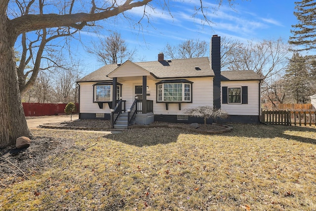 view of front of property featuring a front yard, fence, roof with shingles, and a chimney