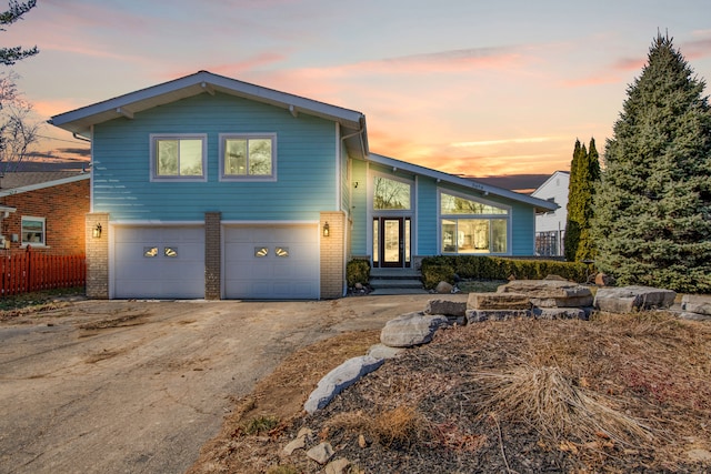 view of front of home featuring brick siding, concrete driveway, an attached garage, and fence