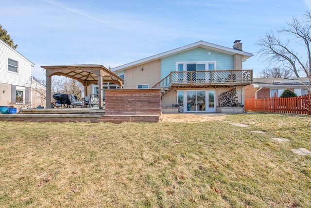 back of property with a deck, fence, a yard, brick siding, and a chimney