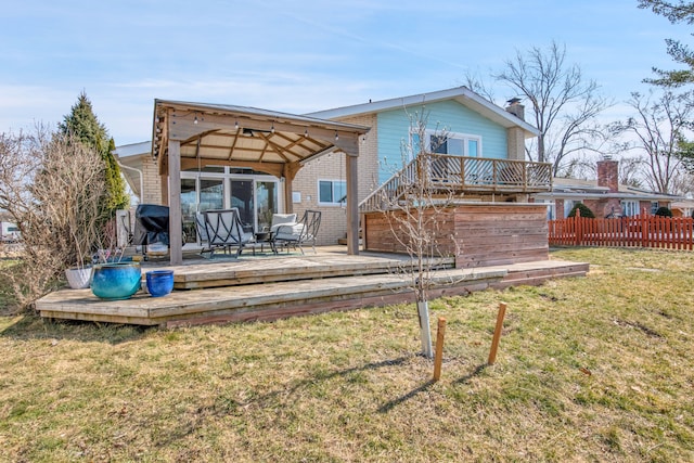 back of property featuring brick siding, a lawn, a wooden deck, and fence