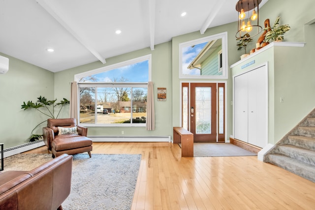 foyer entrance with a wealth of natural light, beam ceiling, hardwood / wood-style floors, a baseboard radiator, and stairs