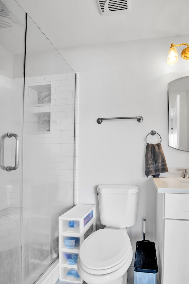 bathroom with vanity, a shower stall, toilet, and visible vents