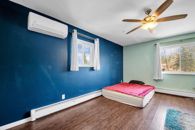 bedroom with baseboard heating, a wall mounted AC, and wood finished floors