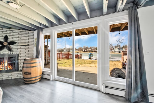 doorway featuring beamed ceiling, a brick fireplace, wood finished floors, and a baseboard radiator