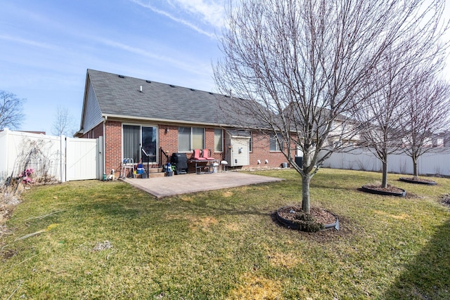 back of house with brick siding, a fenced backyard, a yard, and a patio