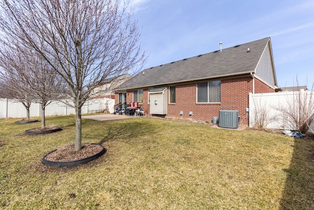 back of property featuring a patio, a fenced backyard, a yard, brick siding, and central AC unit