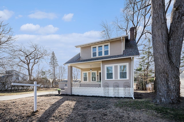 bungalow-style house with covered porch, a chimney, and a shingled roof